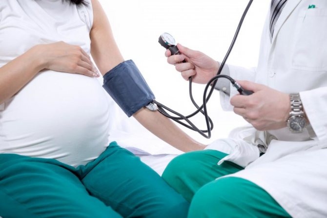 Доктор міряє тиск вагітній жінці