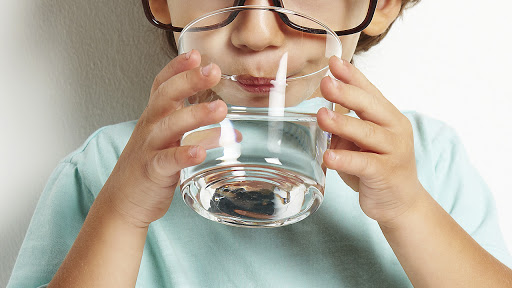 Ребенок пьет чистую воду со скважины 